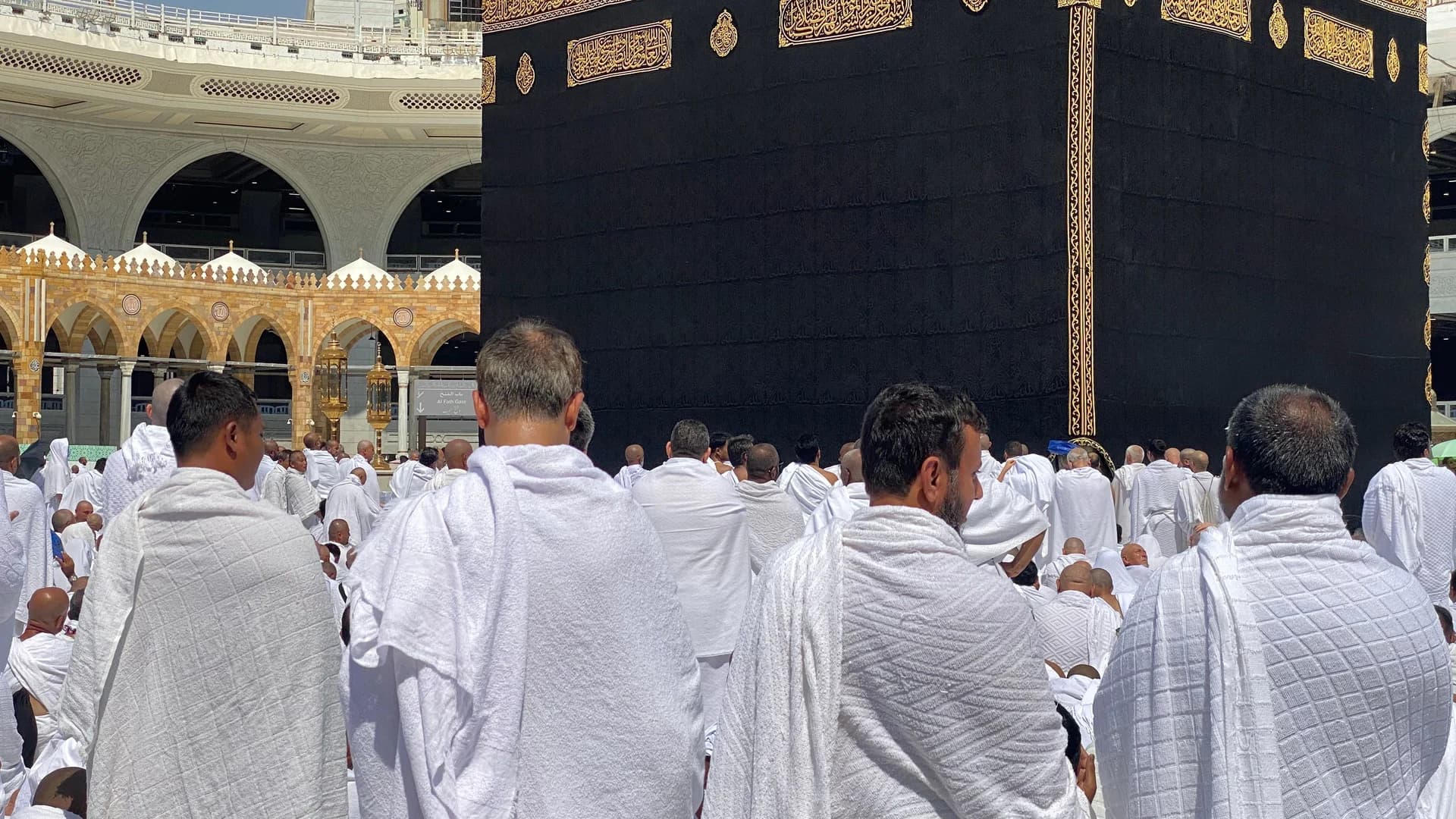 معتمرون بلباس الإحرام أمام الكعبة المشرفة